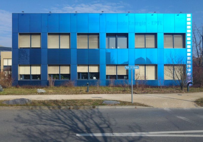 Moderni toimistorakennus, jonka koko julkisivu on verhoiltu kirkkaan sinisillä, sähköä tuottavilla aurinkopaneeleilla